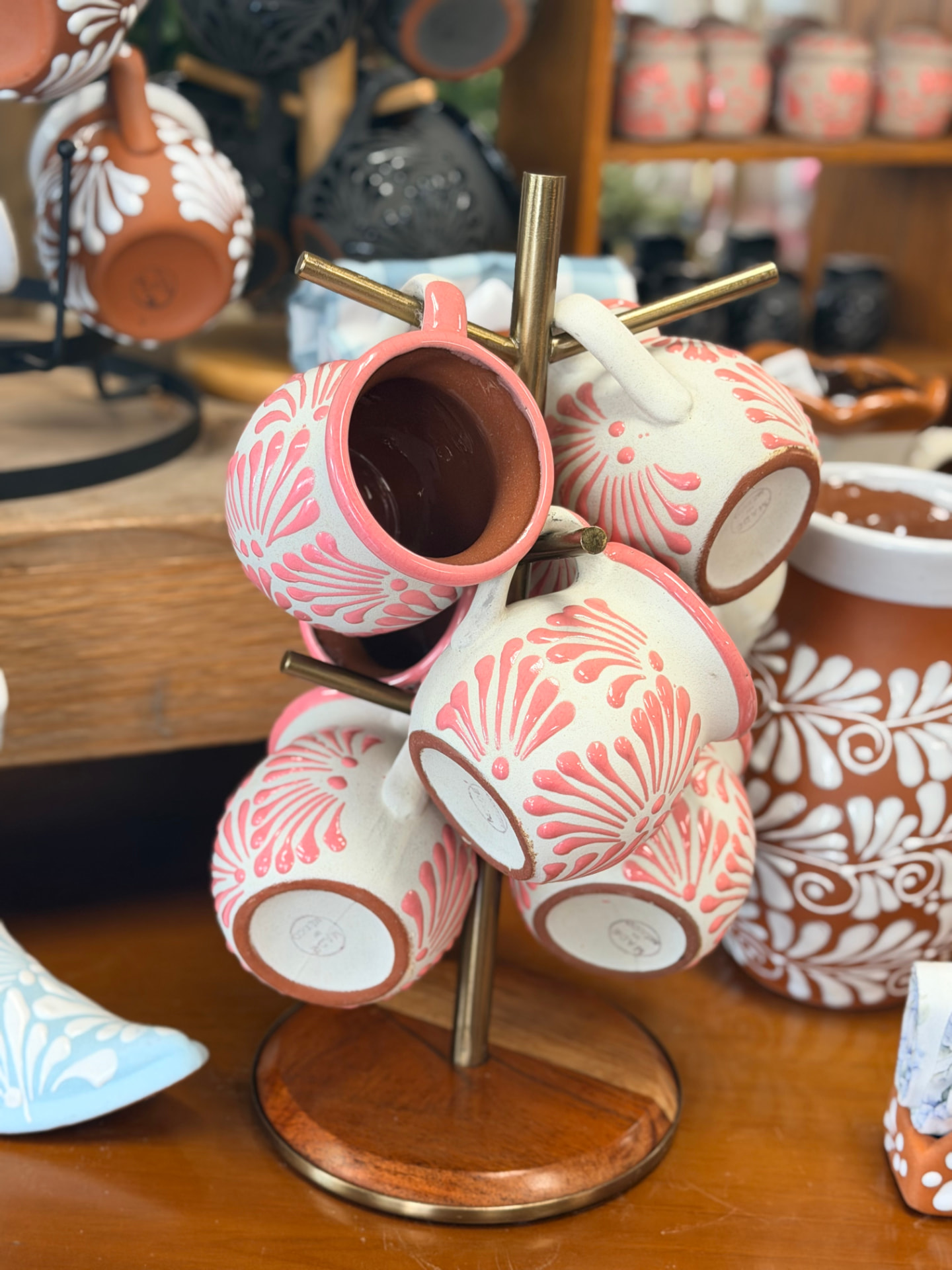 Pink and cream hand-painted pottery mugs on a brass stand