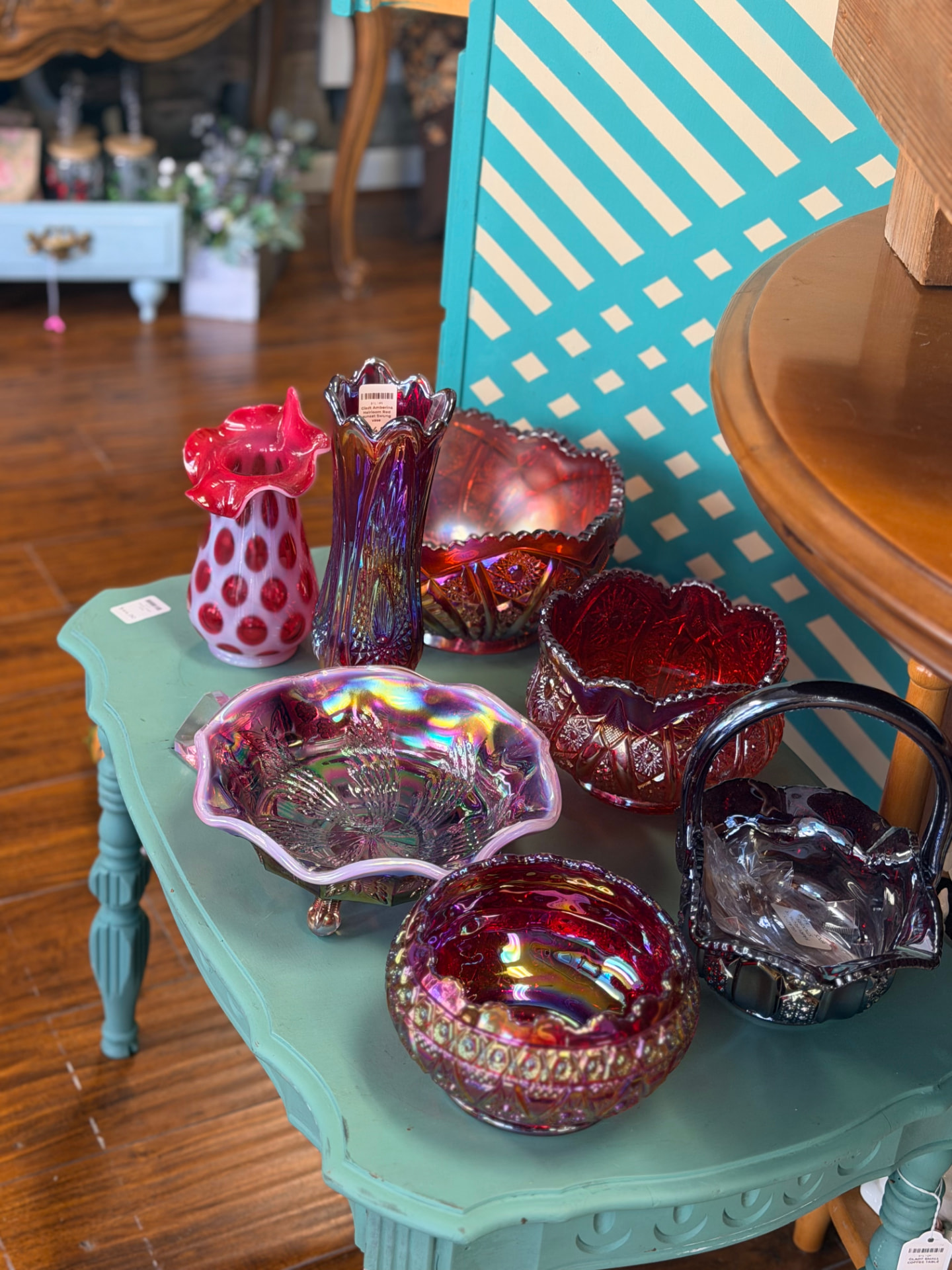 Ruby red carnival and cut glass bowls and vases on a green painted side table